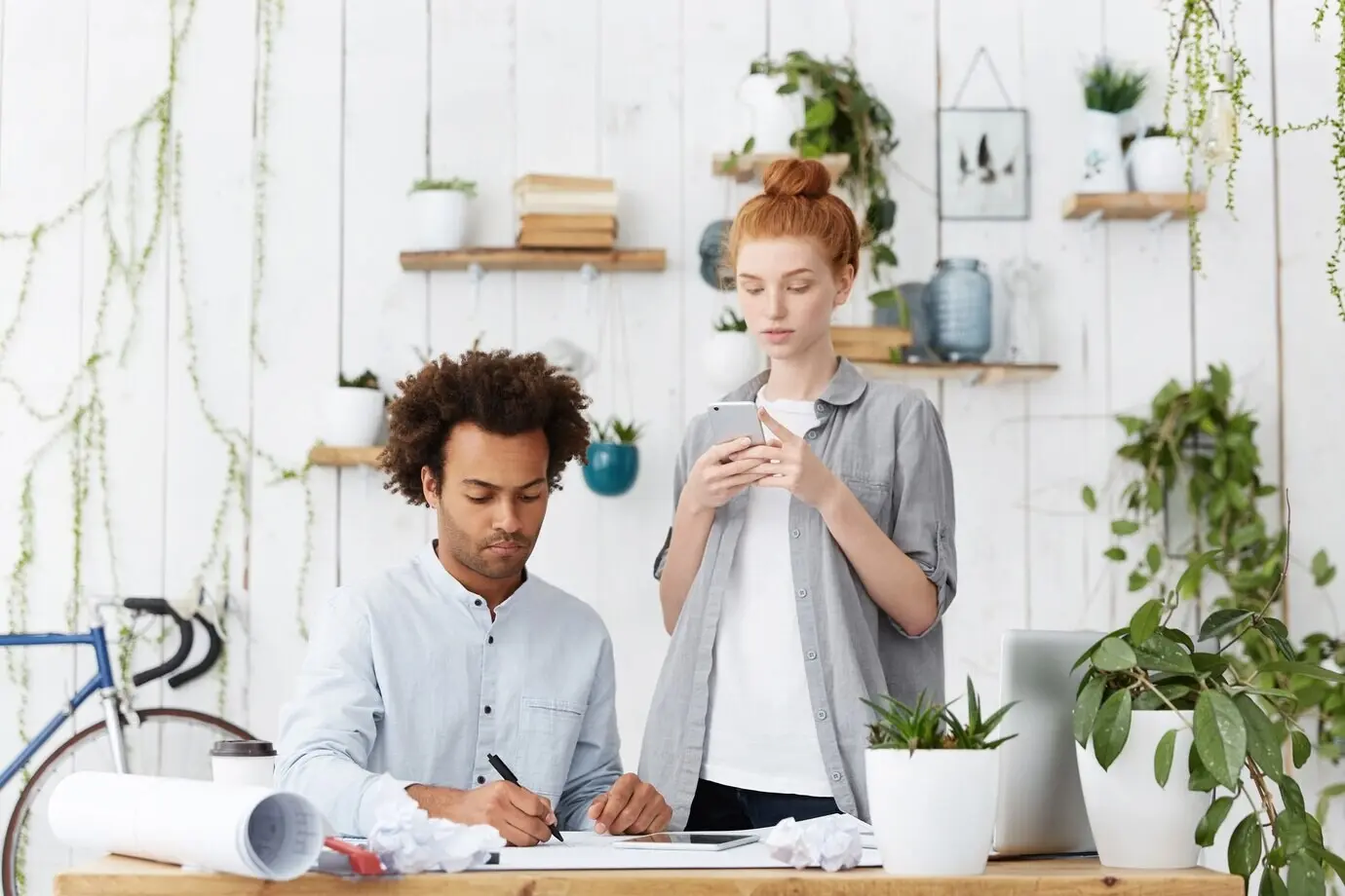 Ernste, konzentrierte afroamerikanische Lehrkraft im blauen Hemd, die Zeichnungen überprüft.