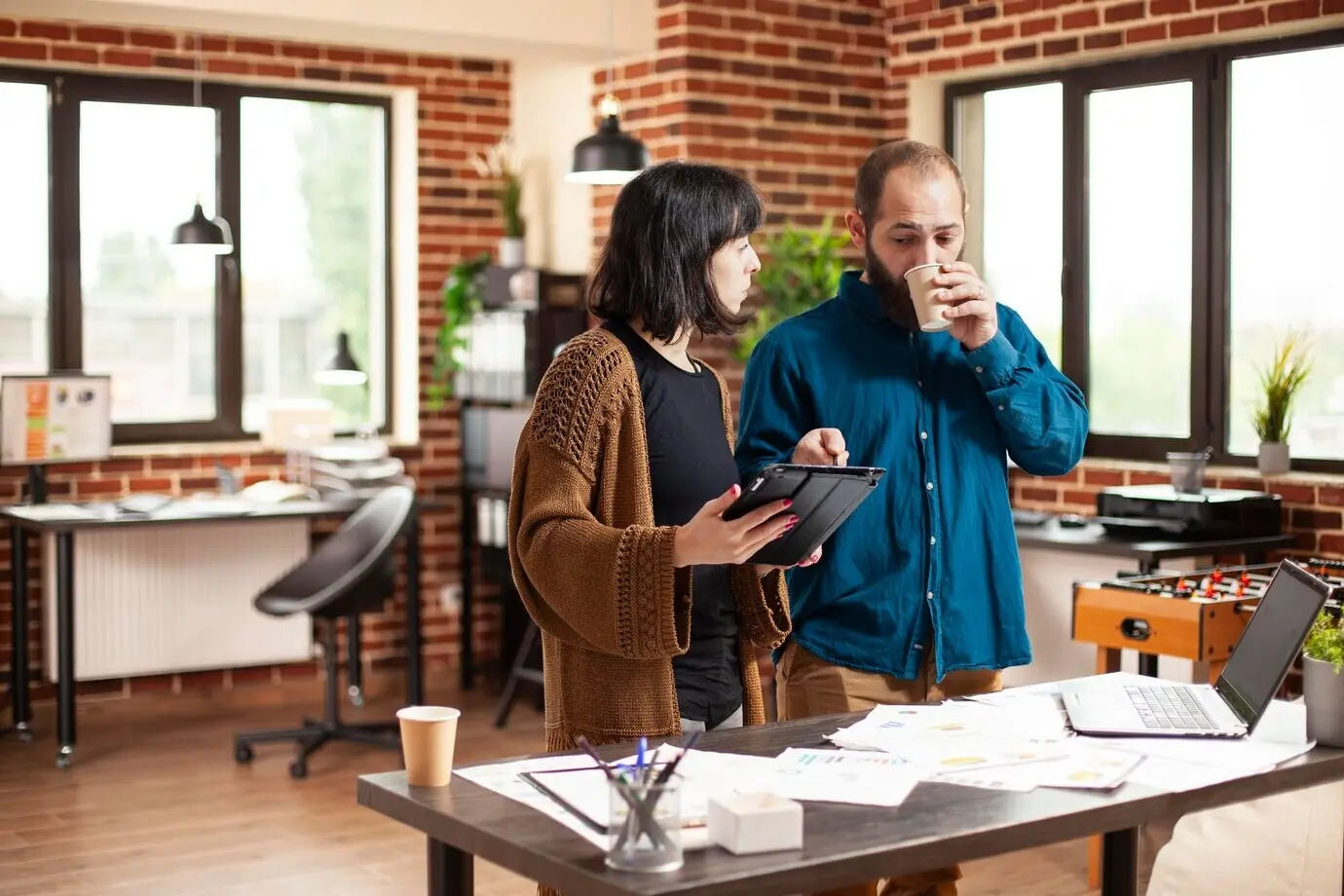 Arbeitskollegen diskutieren mit Tablet und Kaffee.